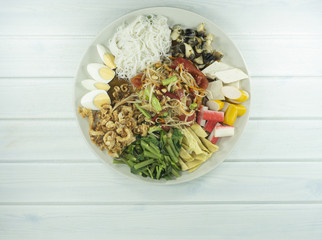 Spicy Green Papaya Salad , Thai style spicy food, Som Tum in a white plate on wood floor table ,Top view Copy Space..