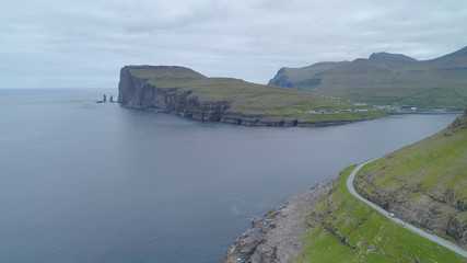 AERIAL: Spectacular rocky cliffs and tranquil sea surround concrete country road