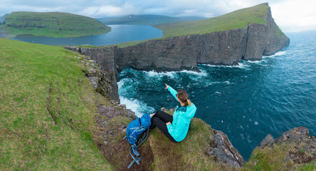 AERIAL: Flying over young female hiker pointing at the spectacular still lake.