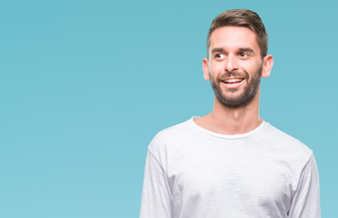 Young handsome man over isolated background looking away to side with smile on face, natural expression. Laughing confident.