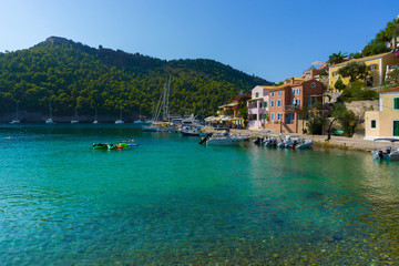 Fototapeta na wymiar View of a bay with turquoise waters and traditional colorful houses in Assos village, Kefalonia, Greece