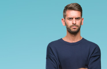 Young handsome man wearing winter sweater over isolated background skeptic and nervous, disapproving expression on face with crossed arms. Negative person.