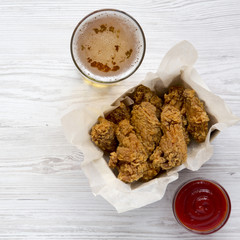 Chicken wings with sauce, cold beer over white wooden surface, top view. From above, flat lay, overhead.