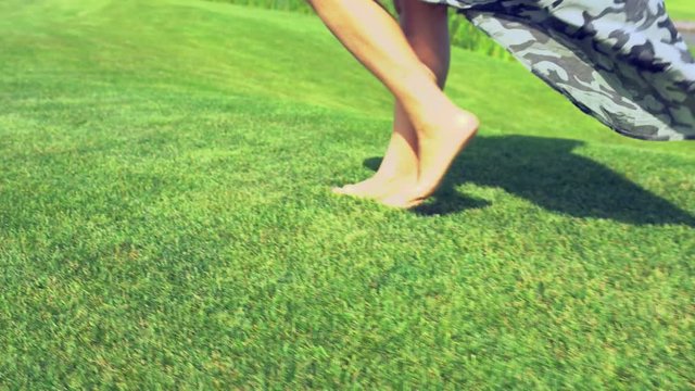 Woman walking bare foot across green grass