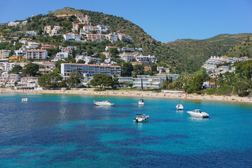 Spain Costa Brava coastal town with sandy beach and boats anchored near the shore, Mediterranean...
