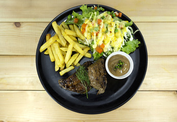 beef steak and French Fries in black dish on wood floor background props decoration with green salad, purple cauliflower,Concept food,Top view.