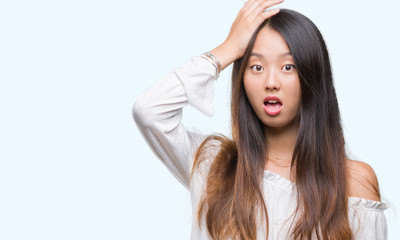 Fototapeta premium Young asian woman over isolated background surprised with hand on head for mistake, remember error. Forgot, bad memory concept.