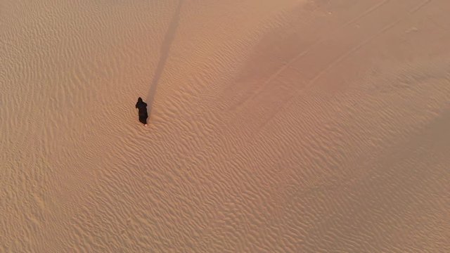 aerial view of a woman in abay walking in a desert