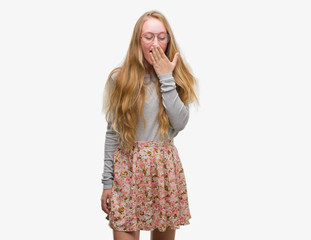 Blonde teenager woman wearing flowers skirt bored yawning tired covering mouth with hand. Restless and sleepiness.