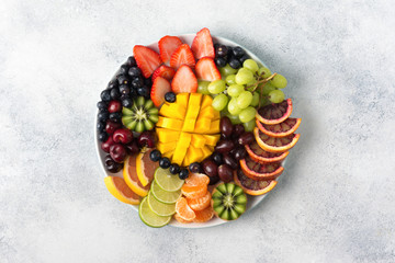Raw fruits berries assortment platter on the white plate, on the off white table, top view, copy...
