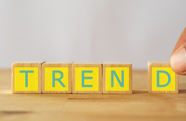 new trend concept, hand man try to complete success the word trend on wood table