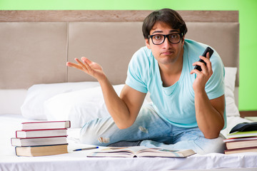 Student preparing for exams at home in bedroom sitting on the be