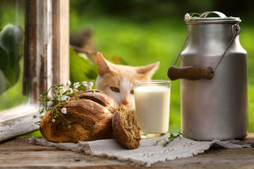 булка ржаного хлеба и молоко  в бидоне на подоконнике