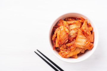 Kimchi cabbage in a bowl with chopsticks on white background, top view, Korean food - obrazy, fototapety, plakaty