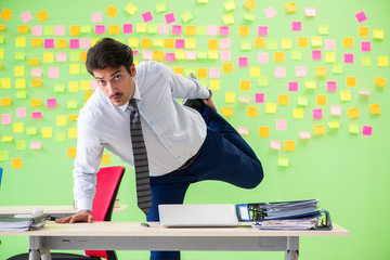 Man in the office with many conflicting priorities doing exercis