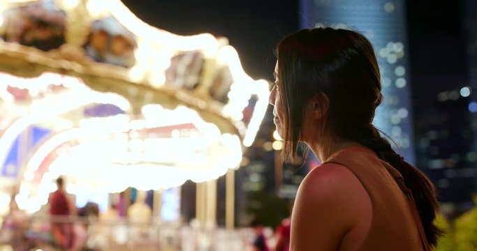 Woman looking at carousel at night
