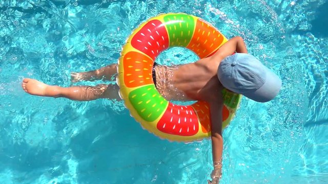 The child swims in the pool with an inflatable circle, slow motion