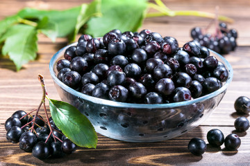 Aronia melanocarpa or black chokeberry in glass bowl on wooden table.Herbalism