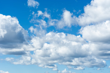 Blue bright summer sky with fluffy clouds on a sunny day