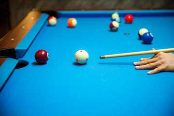 Pool balls on the blue felt pool table with player hands and pool cue stick. Indoor sports. sport and gambling concept. image for background, copy space and article. pocket billiard. cue sports.