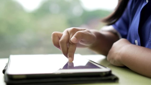 Asian little pupil playing writing on smartphone at the cafe, slow motion shot