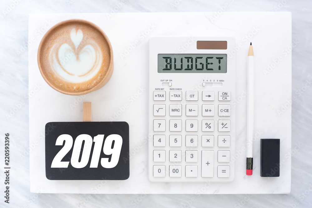 Poster top view of new year 2019 budget on calculator and coffee cup on white marble block and stack on gre