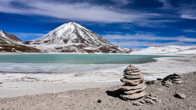 A rock pile stands in front of Laguna Verde and the Licancabur Volcano, Reserva Eduardo Avaroa, Sud Lipez province, Bolivia