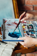 Fototapeta premium art painting hobby. creative lifestyle. artist mixing watercolors preparing to draw picture. ink dyes colorful palette. talent inspiration creation and self expression concept