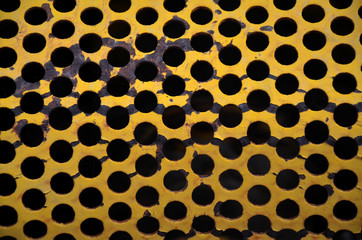 Closeup abstract yellow metal grill with holes pattern 