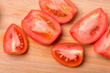 Juicy red tomato chopped on a wooden board on a white background