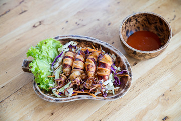 fried squids in wood plate.Steamed squid fried with salty sauce Thai food.Grilled squid and vegetable with spicy seafood sauce on wood table.