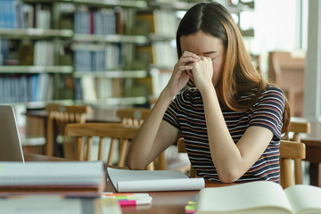 Young girl having eyes tired after reading too much.