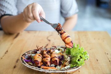fried squids in wood plate.Steamed squid fried with salty sauce Thai food.Grilled squid and vegetable with spicy seafood sauce on wood table.
