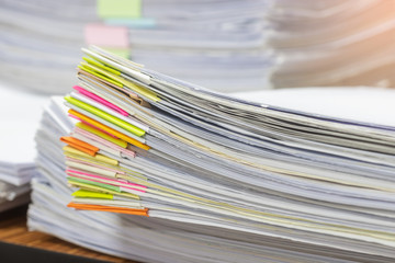 Close up pile of unfinished homework assignment stacked in archive with colorful papers on teacher's table waiting to be managed and inspected. Stack of  paperworks. Education and business concept.