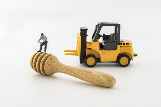 miniature worker working with spoon made of wood on white background.