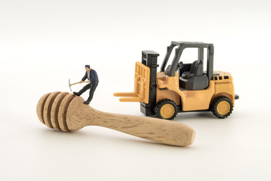 miniature worker working with spoon made of wood on white background.