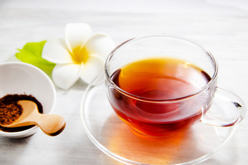透明グラスに入ったノンカフェインのルイボスティー。茶葉とプルメリア。