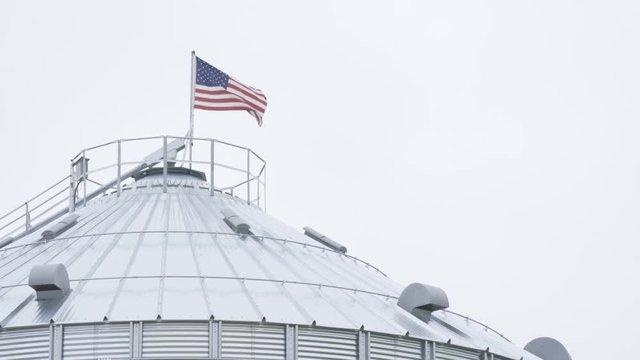 American flag on farm grain silo waving in the wind