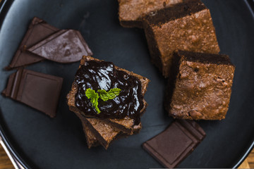 Homemade dark chocolate brownies topping with almond slices and mint stacked on wood table with...