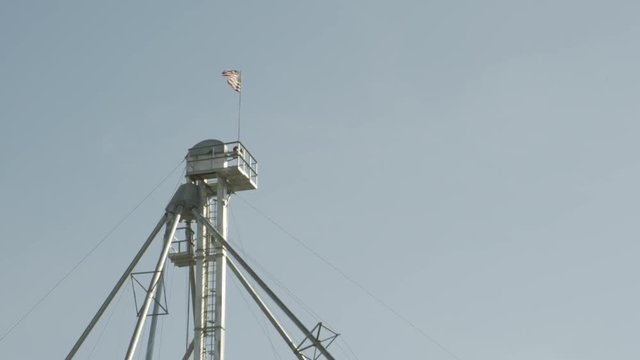 American flag waving on top of industrial metal tower