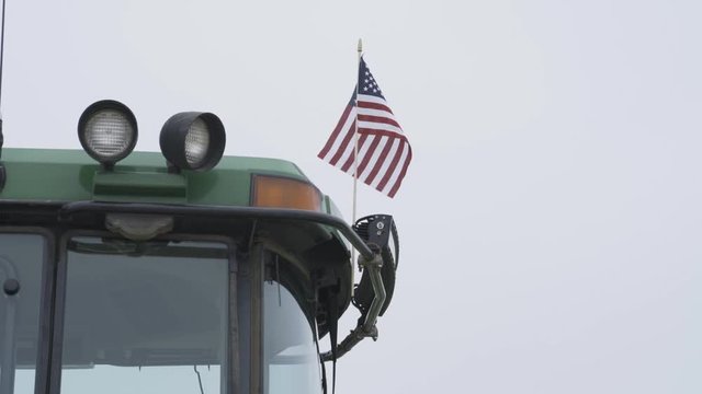 American Flag waving on back of green tractor