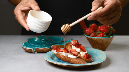 Cooking by chef hands - bruschetta sandwiches with strawberry, cheese and honey on the whole grain roasted bread