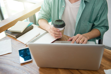 Business male hands typing on a laptop keyboard on desk with a cup of coffee in evening light,Urgent agenda,Freelance work at home office.