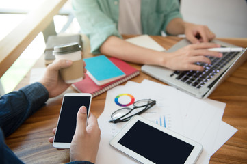 business team  briefing marketing strategy with smart phone, tablet, notebook, and laptop on wooden desk with,Freelance work at home office. Writing note on a book.