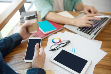 business team  briefing marketing strategy with smart phone, tablet, notebook, and laptop on wooden desk with,Freelance work at home office. Writing note on a book.