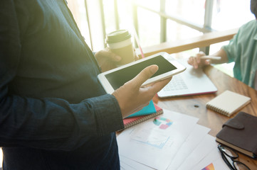 business team analyzing marketing strategy with smart phone, tablet, notebook, and laptop on wooden desk with,Freelance work at home office.Team work and helping hand