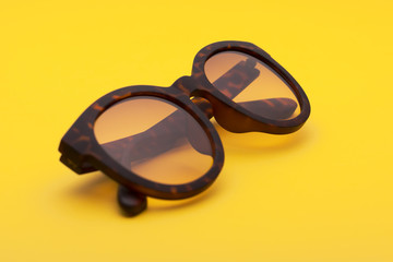 A pair of tortoises shell style fashion glasses isolated on yellow background.