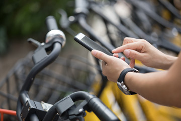 People hands using smartphone scanning the QR code of shared bike in city