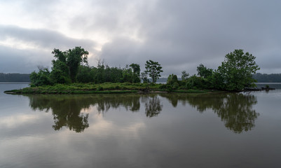 Fototapeta premium A cloudy sunrise creates a perfect reflection of an island off the marshy waters.