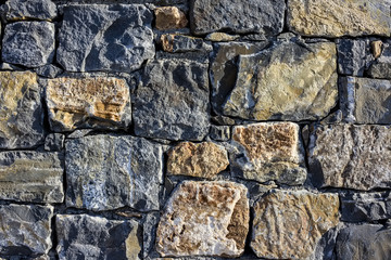 large wall of natural granite stones of different size and color, gray texture on a summer day, multi-colored granite natural stone, pieces of stone, splinters, texture pattern,